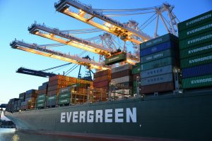 A cargo ship docked at a seaport surrounded by cranes and stacked shipping containers, representing Bank Financial instruments key insights and the uses of bank instruments in international trade. Artley Finance (HK) Limited is a Bank Financial Instrument Provider/Monetizer. 