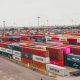 A stack of shipping containers at a busy seaport, symbolizing secure international trade facilitated by Bank Payment Undertaking (BPU).